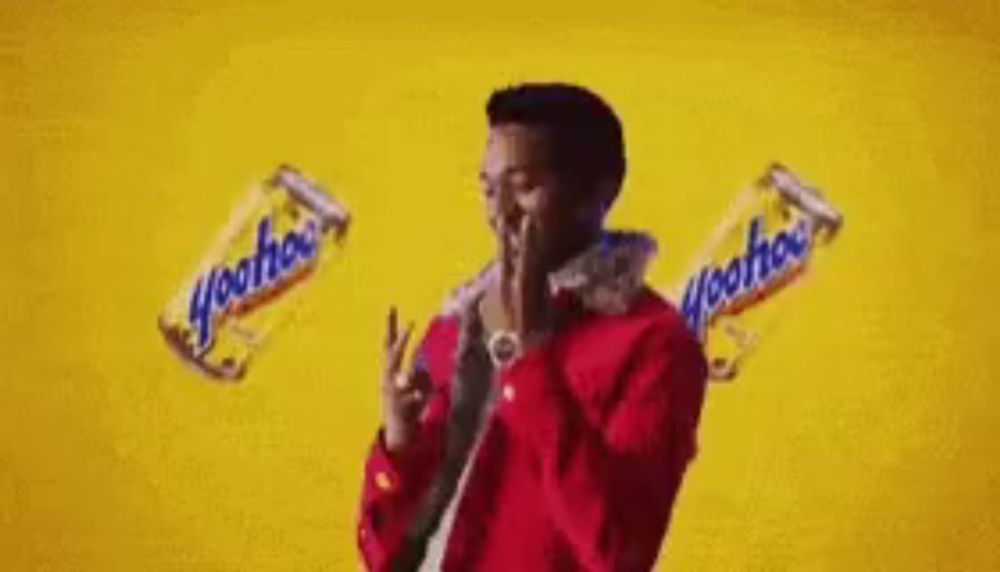 a man in a red jacket is holding a bottle of soda while dancing .