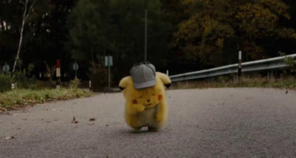 a small stuffed animal wearing a hat is walking down the road