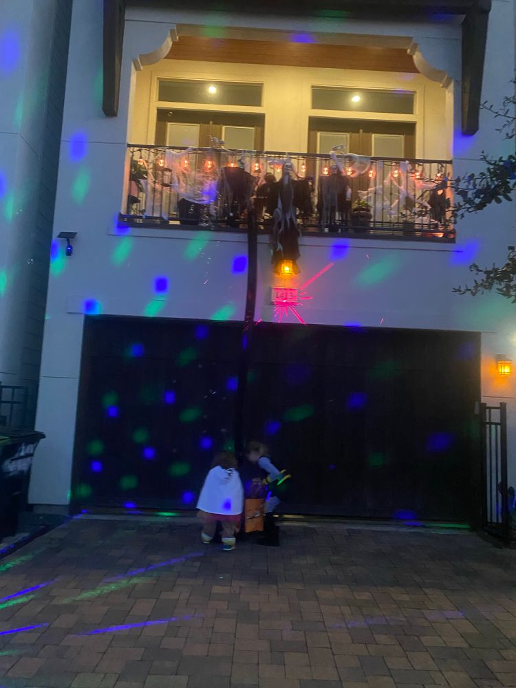 Spook Halloween decor above of a garage door. A ramp from the balcony delivers candy to two trick or treaters. 