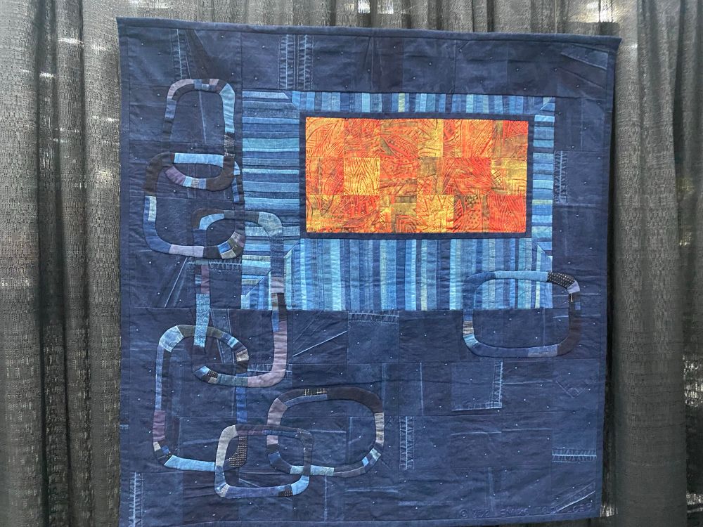 An abstract quilt featuring a rectangle in orange over a field of blue. It’s very complicated. 

Renaissance by Emiko Toda Loeb
New York, NY
USA
Techniques: Hand appliqué, embroidery, and quilting; machine piecing and quilting
Design Source: Original design
As one grows older changes of weather or feeling are said to have less effect, but for me they stay the same. Whether I am happy or sad, I want to project that feeling into my quilts. This is the first quilt done with that intention. Look at the quilt and guess whether I was happy or sad while making it.