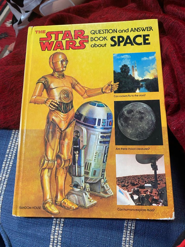 The Star Wars Question and Answer Book About Space. The cover features a picture of C-3PO and R2D2 with insets of a rocket taking off (Can rockets fly to the stars?), a picture of the moon (Are there moon creatures?), and a picture of the surface of Mars (can humans explore Mars?)