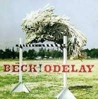 The cover of Beck’s Odelay album, which features a white corded Komondor leaping over an acequia hurdle. 