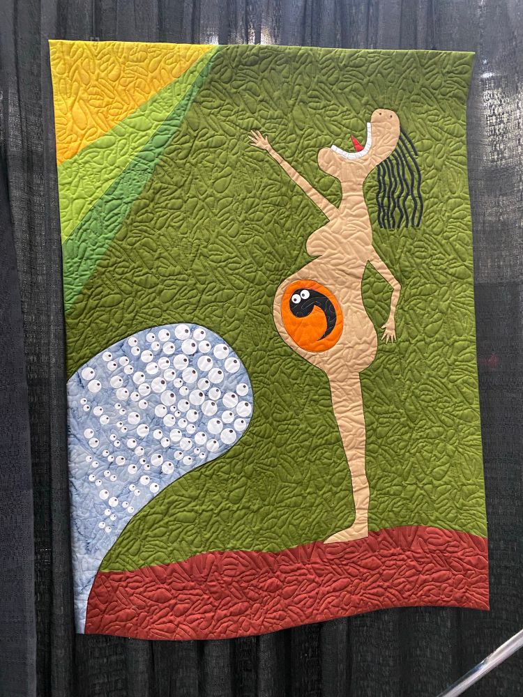 A quilt depicting a sketch of a pregnant woman shouting into the void. A googly eyed creature is in her belly, Several other googly eyes are aimed at her in a sort of grey wave. She’s on a green background and standing on a red surface. 

Expecting Expectations by Karen Diane Morgan Guthrie
Altadena, CA
USA
AVAILABLE FOR PURCHASE
Techniques: Hand painting; machine appliqué and quilting; thread sketching; fusing; ink painting
Design Source: Original design
New and expecting mothers and their babies suffer a barrage of opinions and criticism. All the choices made by the parents are scrutinized and judged - along with the behavior of the child - often by their families and friends, who should be loving and supporting their choices. Being a parent is a mindbogglingly difficult task, lasting for decades.
Wouldn't the world be a better place if we all just let parents choose for their family?