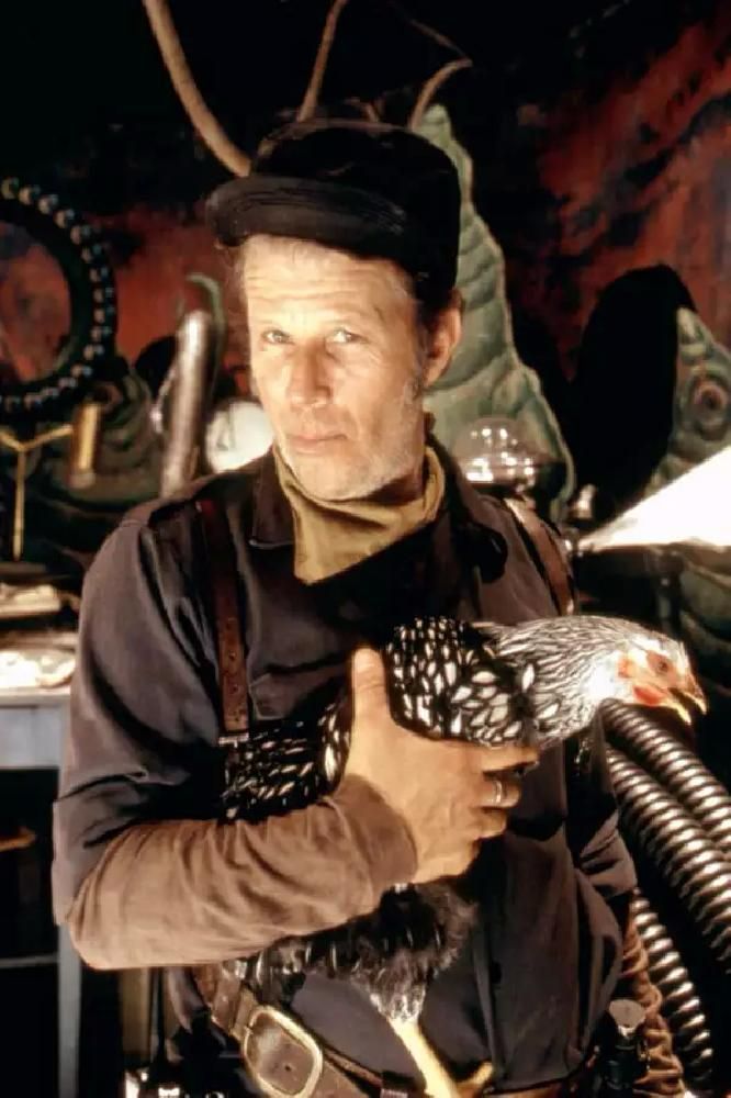 Tom Waits in steam punk-esque garb holding a chicken. 