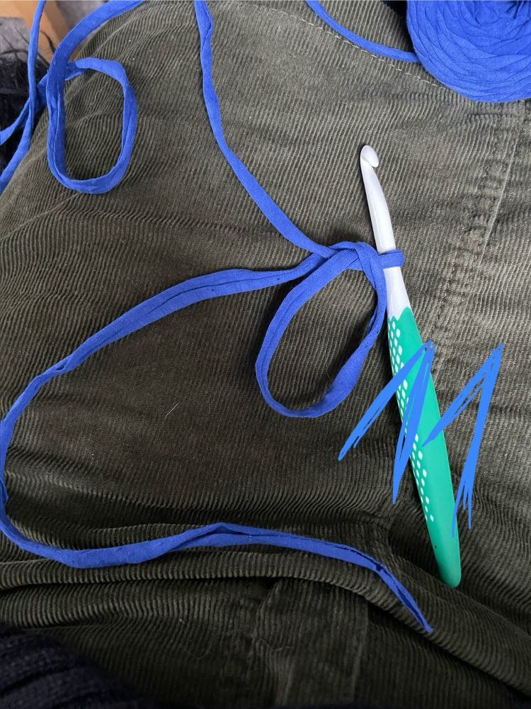 So muss das dann aussehen. Der Faden auf dem Knäuel kommt von oben und macht mit eine kleine Schlaufe mit der Häkelnnadel dann geht der Faden weiter und eine größere Schlaufe liegt auf dem Faden, der aus dem Knäuel kommt. Das Fadenende schlängelt sich über das entstandene Fadenkreuz, und dann taucht es unter dem Faden vom Knäuel durch.