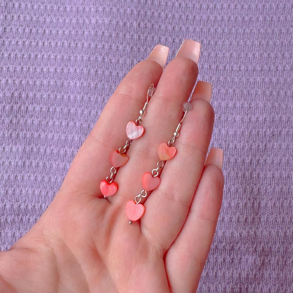 hand holding earrings with three cascading pink abalone shell hearts 