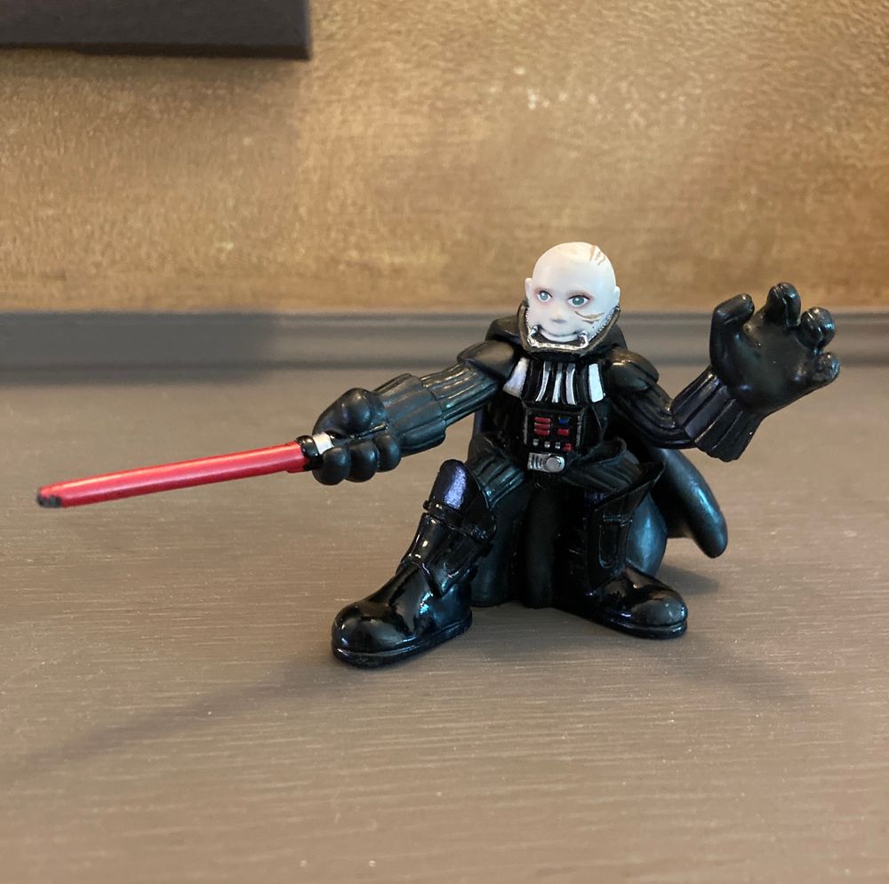 Action figure of Darth Vader, without his helmet, wielding a red light saber