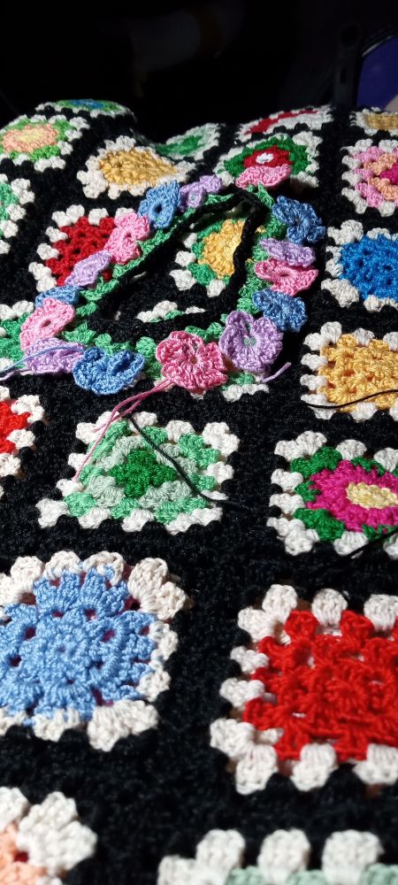 Crochet shirt of various colours and types of squares. A cuff consisting of simple flowers.
