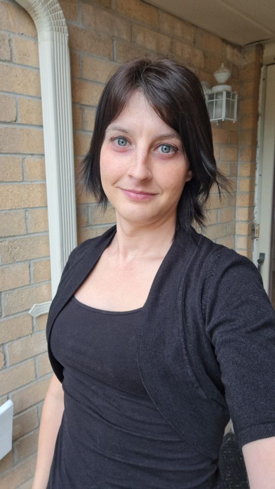 Selfie outside my front door, taken today (over 8 months on HRT). Hair has since been dyed black, and I have a bit more talent with makeup.