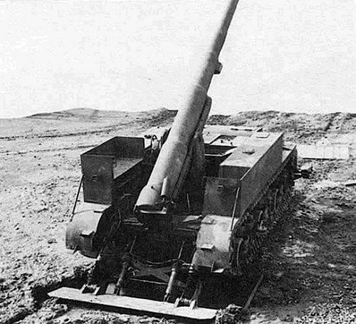 A black and white photo of an M12 self propelled howitzer. Its rear spade is dug into the ground behind it, which helps prevent stress on the vehicle's suspension when firing the gun.