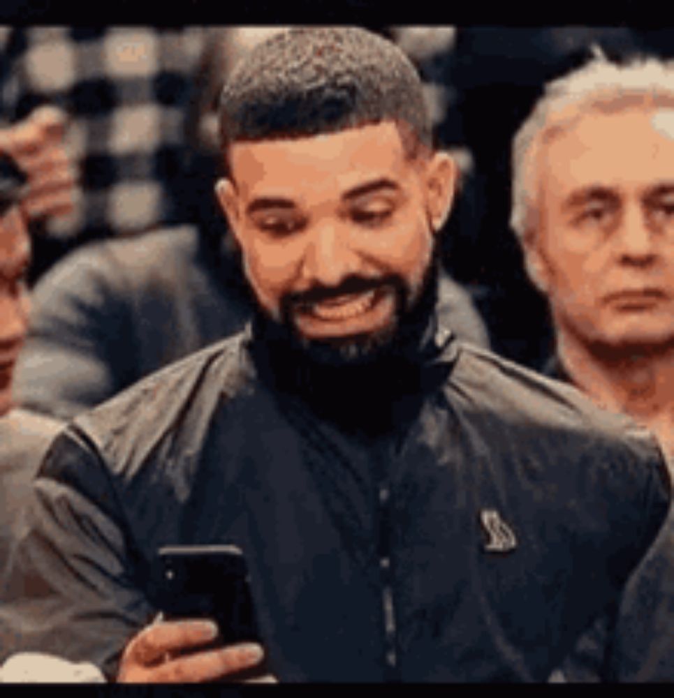 a man with a beard is smiling while holding a cell phone in his hand .