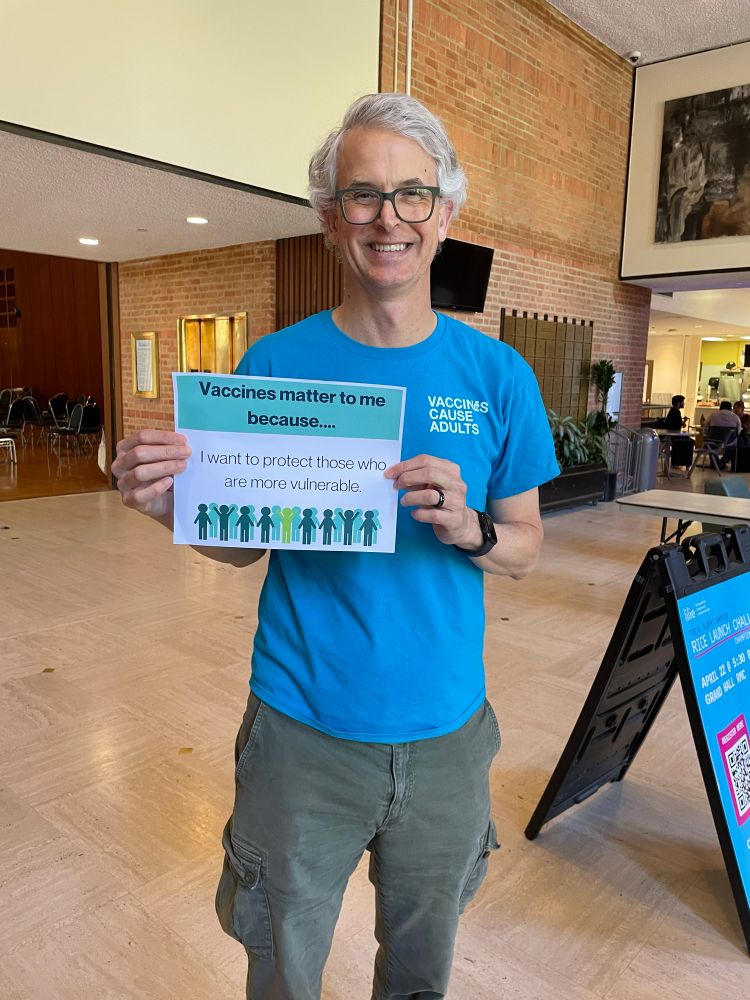 Middle age professor holding a sign that says “Vaccines matter to me because I want to protect those who are more vulnerable.”