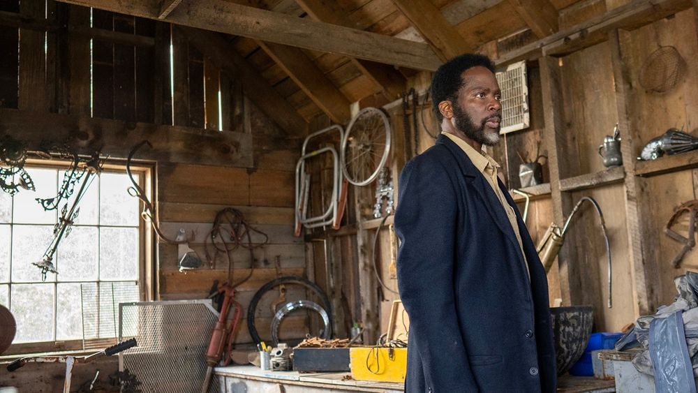 Harold Perrineau stands in a shed and looks toward something out of frame. 