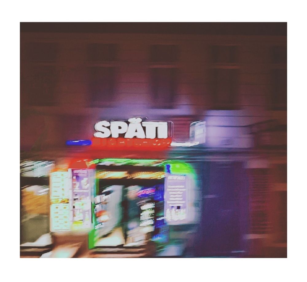 Aus der U-Bahn fotografiert und sehr verschwommen. Nachtaufnahme, Leuchtschrift Späti weiss erkennbar sowie ein beleuchteter Eingang in das Ladengeschäft, etwas Grünlicht