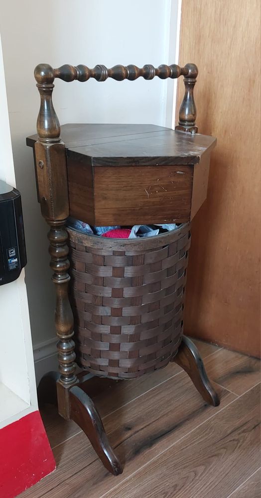 A cool vintage sewing basket/table of dark wood with a beveled handle above it.