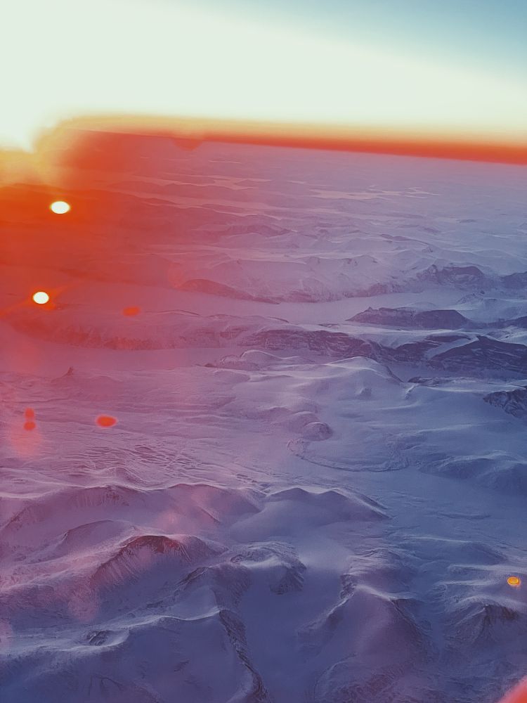 Low sunset from airplane over Greenlands icy mountains 