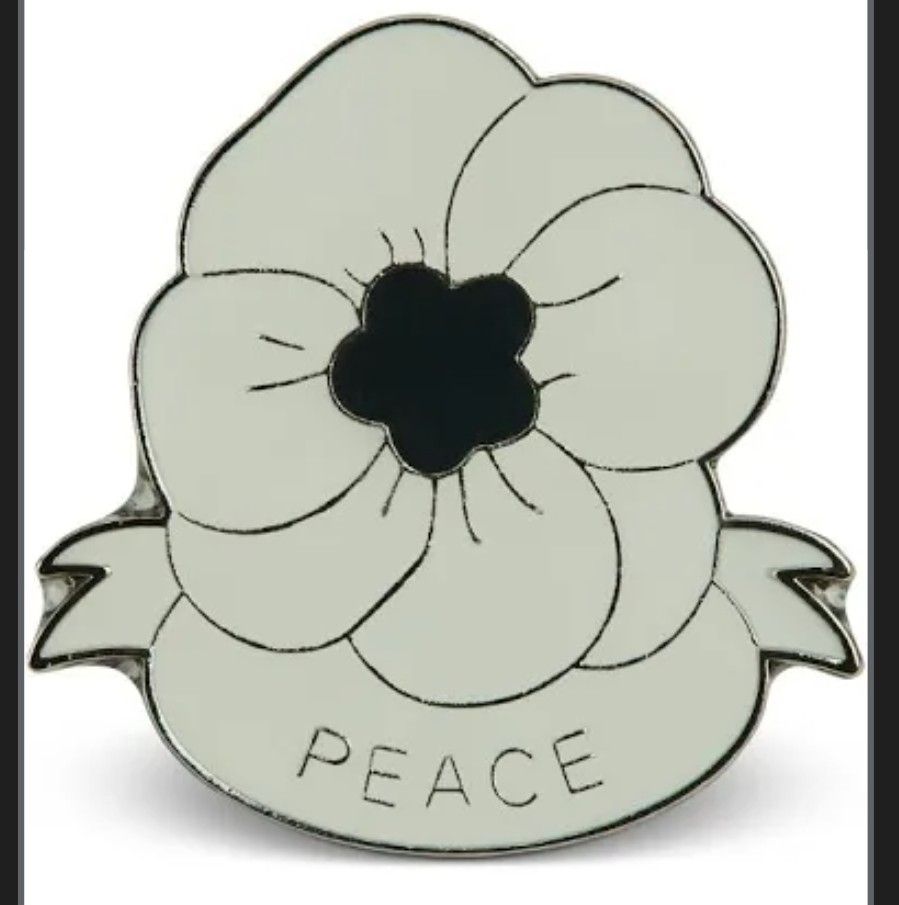 A badge of a white poppy with a banner underneath reading "PEACE"