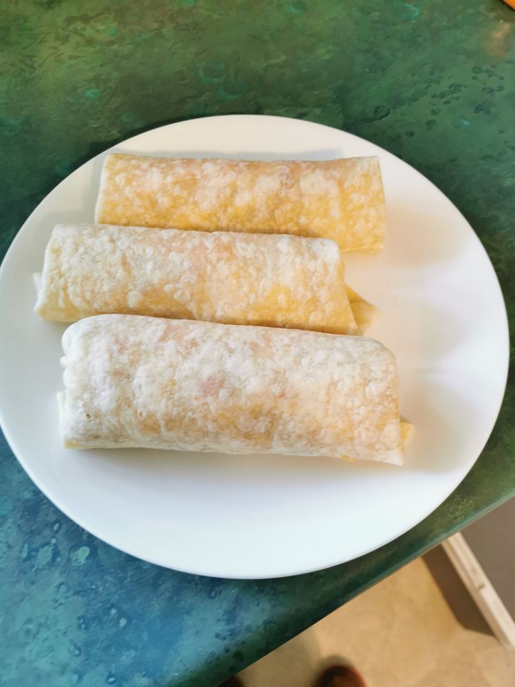 Picture of 3 burritos on a plate ready to be eaten. 