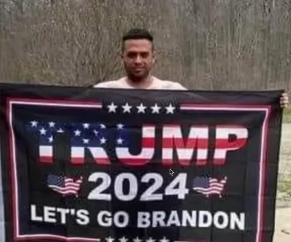 Héctor Luis Valdés Cocho holding up Trump 2024 Let's go Brandon Flag
