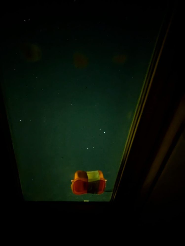 SkyPro, a GoPro in a plastic box, sat on a skylight with diffuse green glow from the aurora in the sky.
