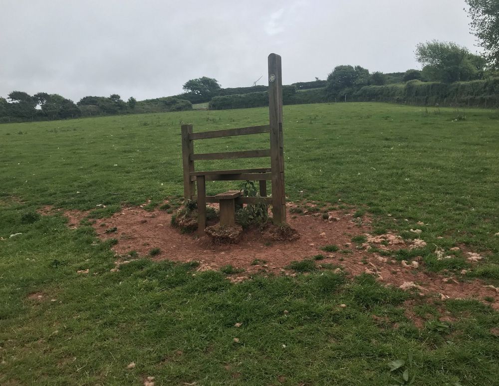 A stile in the middle of a field, surrounded by no hedging or fence.