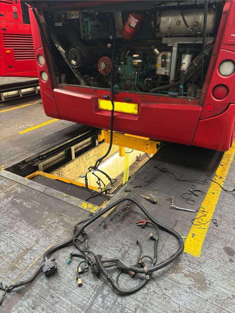 Commercial bus with the bonnet up showing the engine electrical loom being removed and replaced.