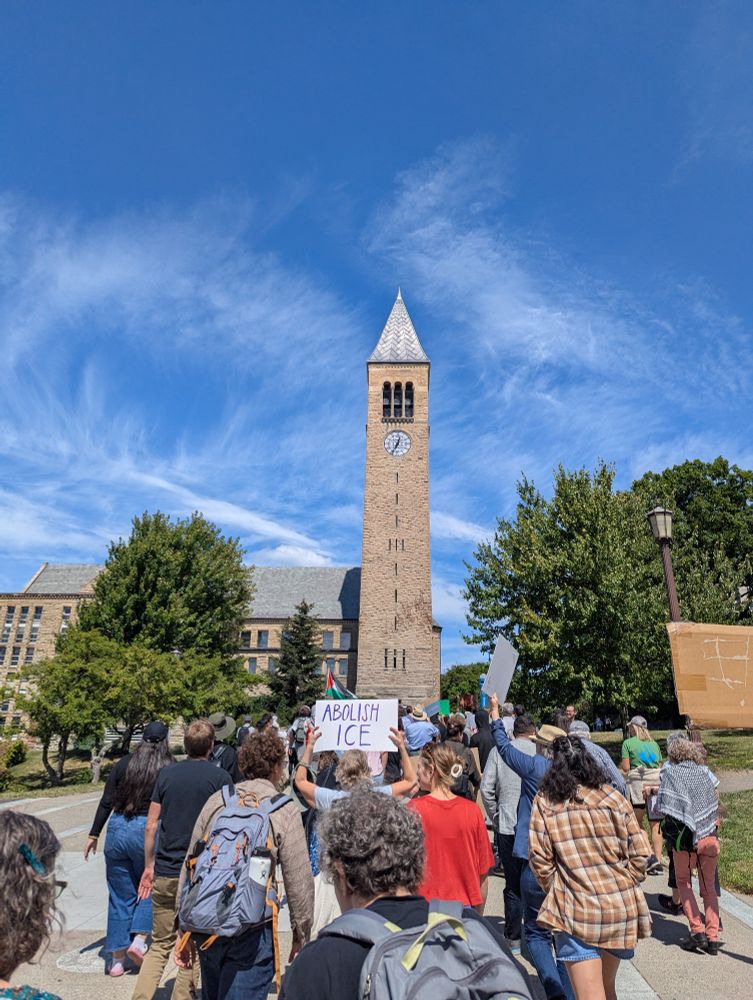 Picture of McGraw Tower at Cornell with protestors holding a sign that reads ABOLISH ICE 