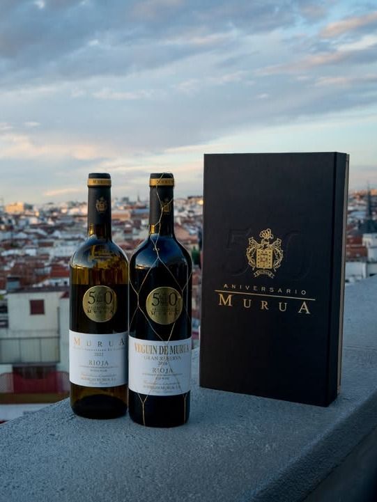 Dos botellas de vino blanco y tinto de la bodega Murua, con etiquetas que celebran el 50 aniversario, junto a una caja conmemorativa.
