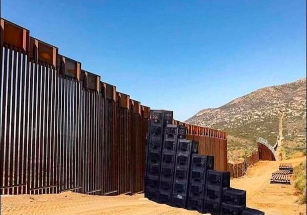 The southern border wall with a stack of milk crates to make stairs to climb over.