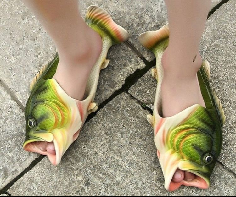 Slide-on slippers that are made to look like fish. The mouth of the fish are completely open, revealing the model’s toes