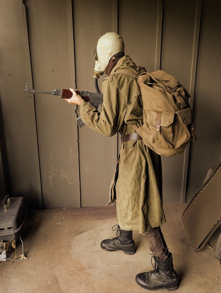 HROT Smaskou Cosplay; a zombie Soldier wearing a trench coat and non-functional gas mask, holding a replica VZ-58 rifle prop.