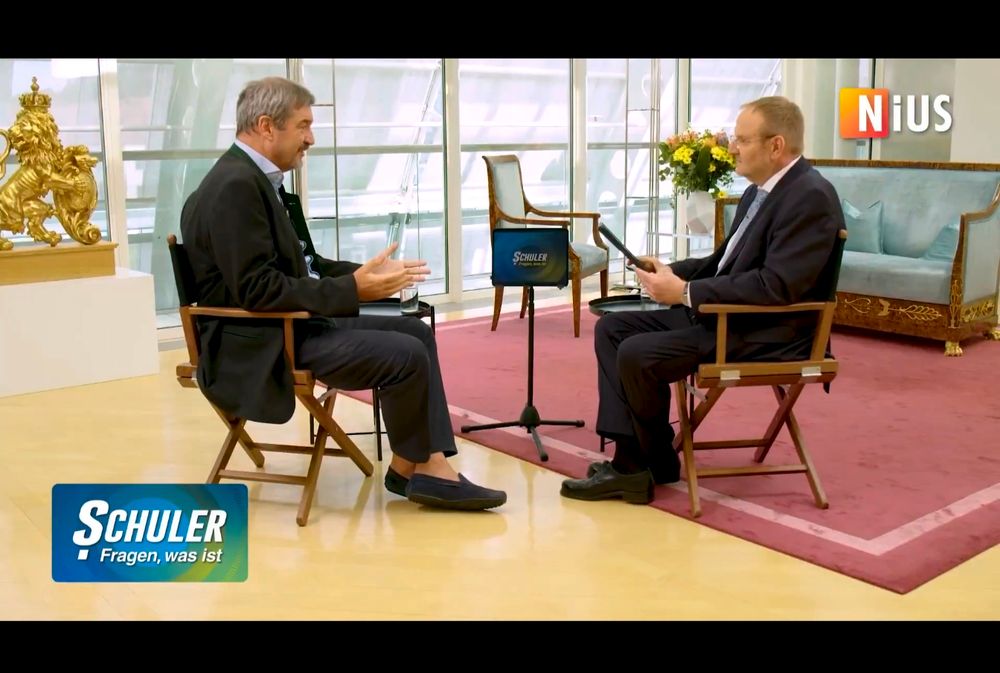 Fotostull des Interviewvideos. Söder und Schuler sitzen sich gegenüber in der Bayerischen Staatskanzlei 