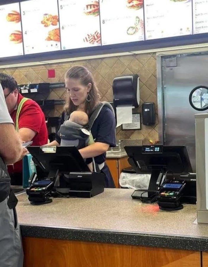 Foto: Kasse einer Fastfoodkette: Eine Frau mit umgeschnallten Baby kassiert.