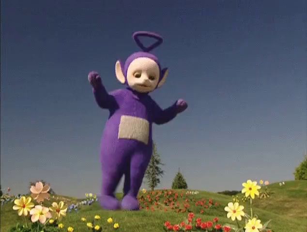 a purple teletubbies standing in a field of flowers