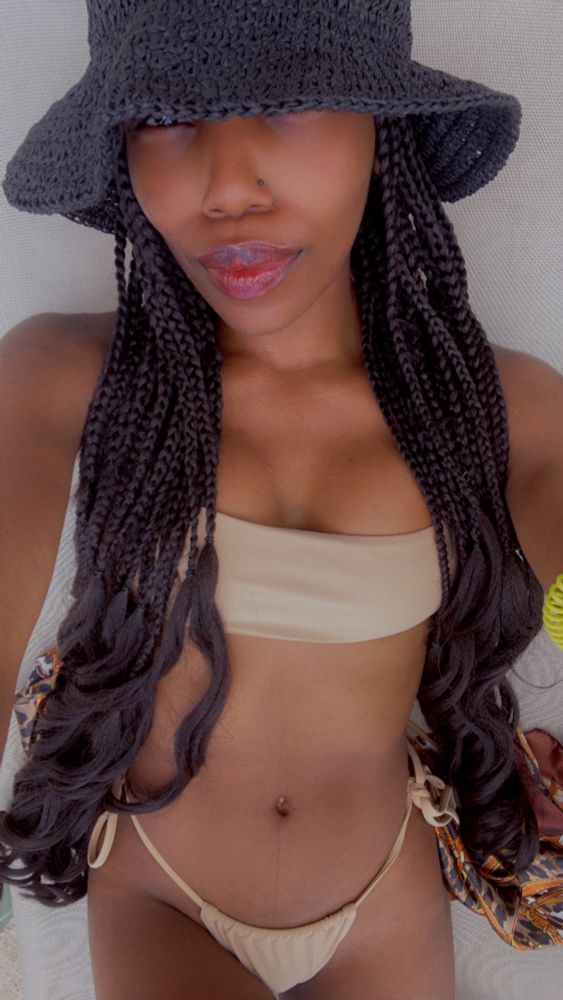 Black woman on the beach in a bikini and a black sun hat in costa maya Mexico. 