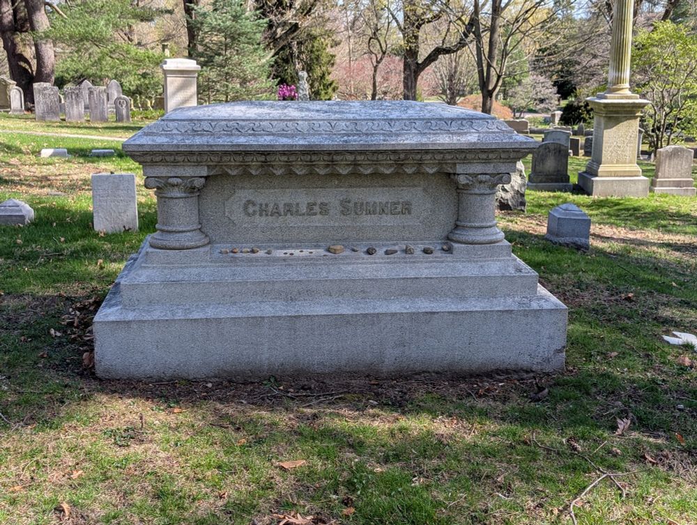 A rectangular stone monument with a low double plinth perhaps 18" high, above it columns at the corners. Chiseled on it the name Charles Sumner. A number of small stones have been left atop the plinth, as you might do at a Jewish grave.