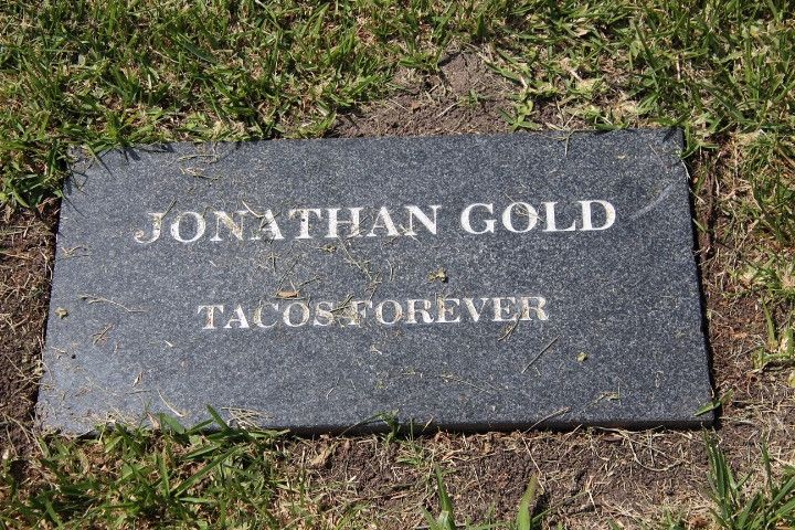 A gray headstone, probably granite, inscribed as follows:

JONATHAN GOLD

TACOS FOREVER