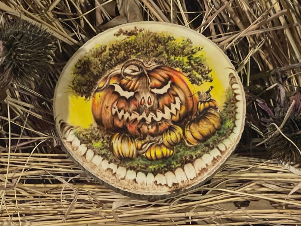 Woodburn and colored pencil drawing of a maniacally grinning orange pumpkin in a pumpkin patch resting on a bed of human teeth. 