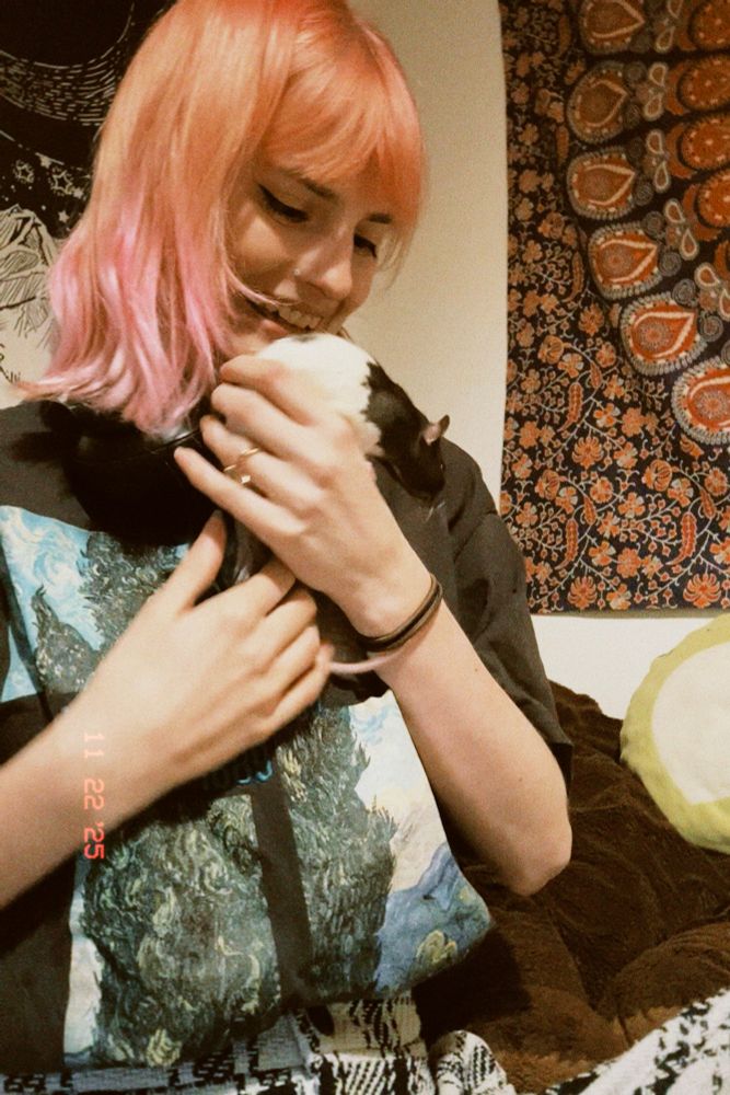 a photo of me, holding a black and white rat that’s about to run down my arm 