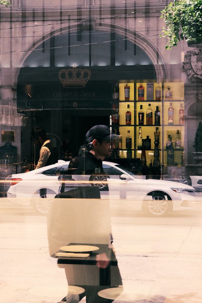 Reflection of man walking while seeing into a bar through a window