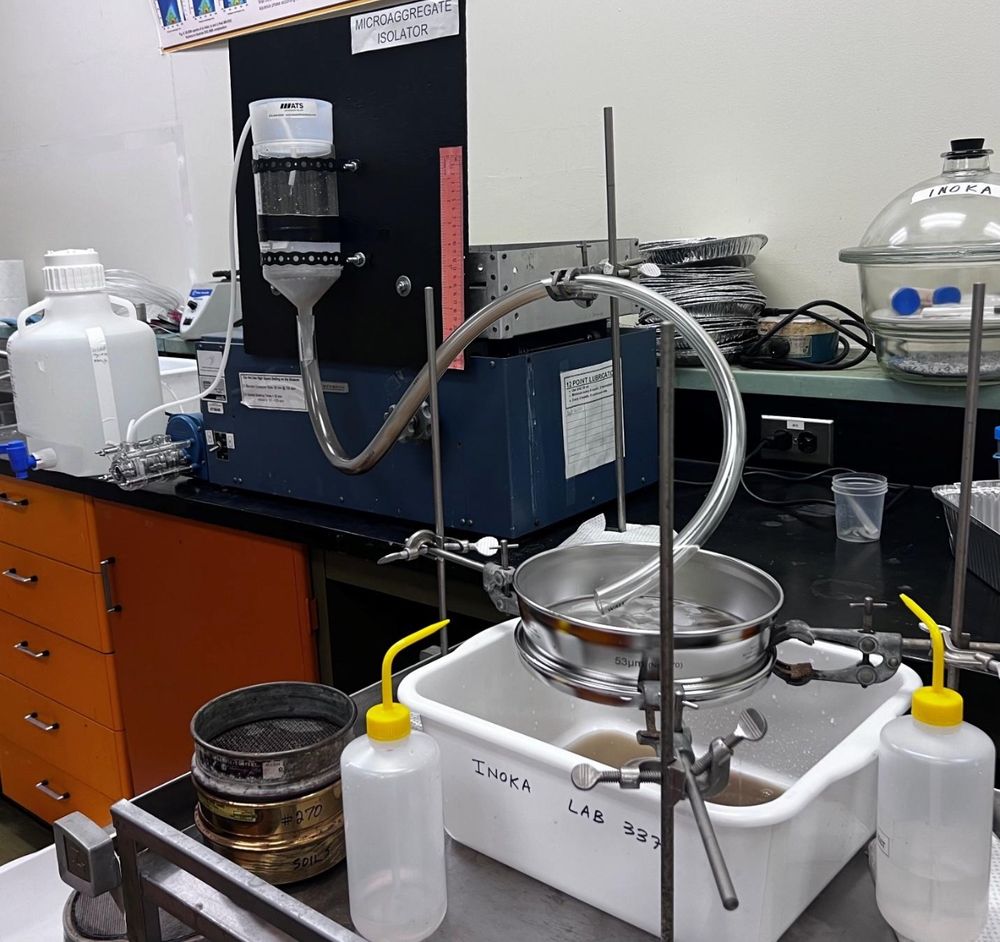 Lab equipment set up for testing. Several water bottles, a stainless bowl with a tube dripping into it and a basin below to collect overflow.