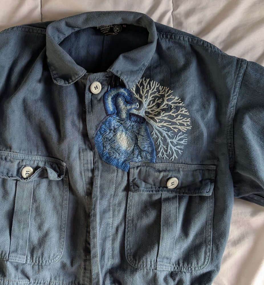 Broderie représentant un coeur et des bronches en monochromie bleue sur une combinaison de travail bleue