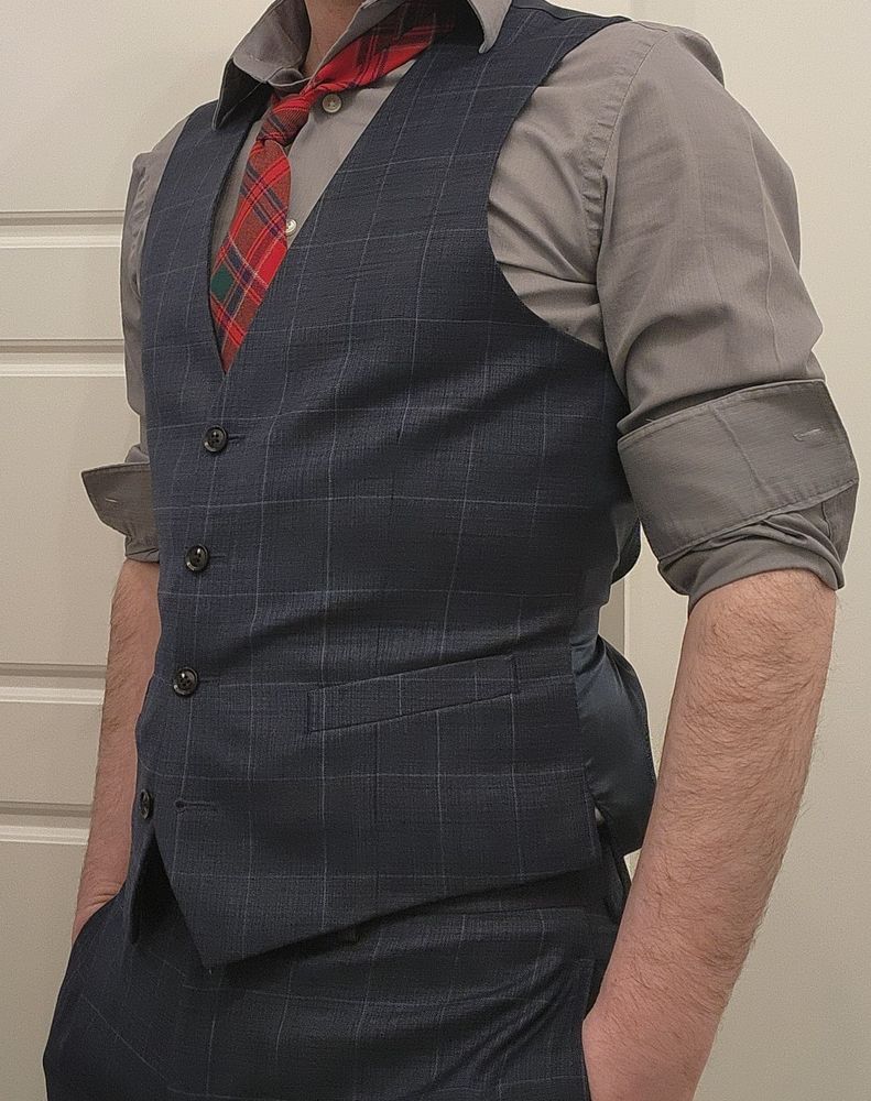 Slim fellow in a blue vest and red plaid tie with rolled up sleeves
