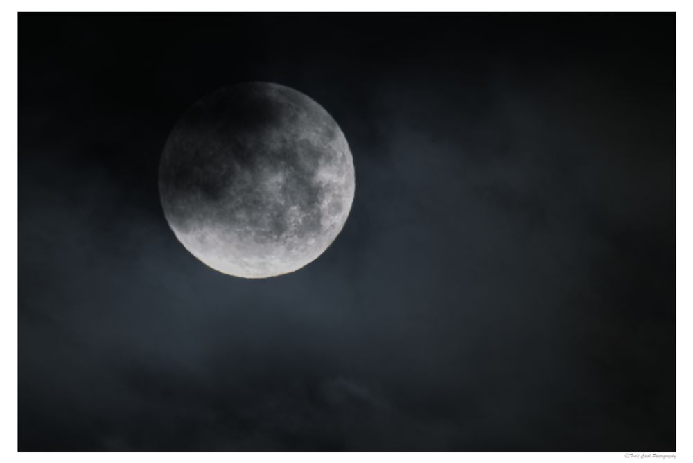 The February full Snow Moon partially obscured by clouds.