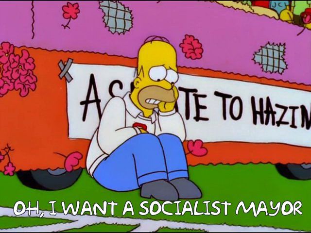Homer Simpson sitting in front of a bus opining that he wants a socialist mayor