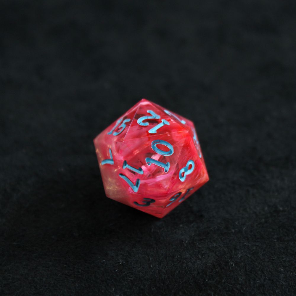 A single bright orange-pink d20 with bright blue numbers. The die is resting on a black background. There are hints of shimmering gold at one end of the die.