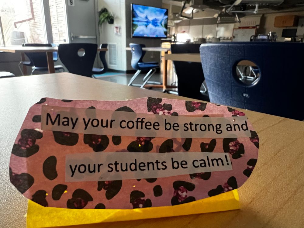 Pink leopard print handmade card sits on a teacher desk in a science room. The card reads, “May your coffee be strong and your students be calm!”  