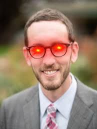 Man in a grey suit with black glasses and laser eyes