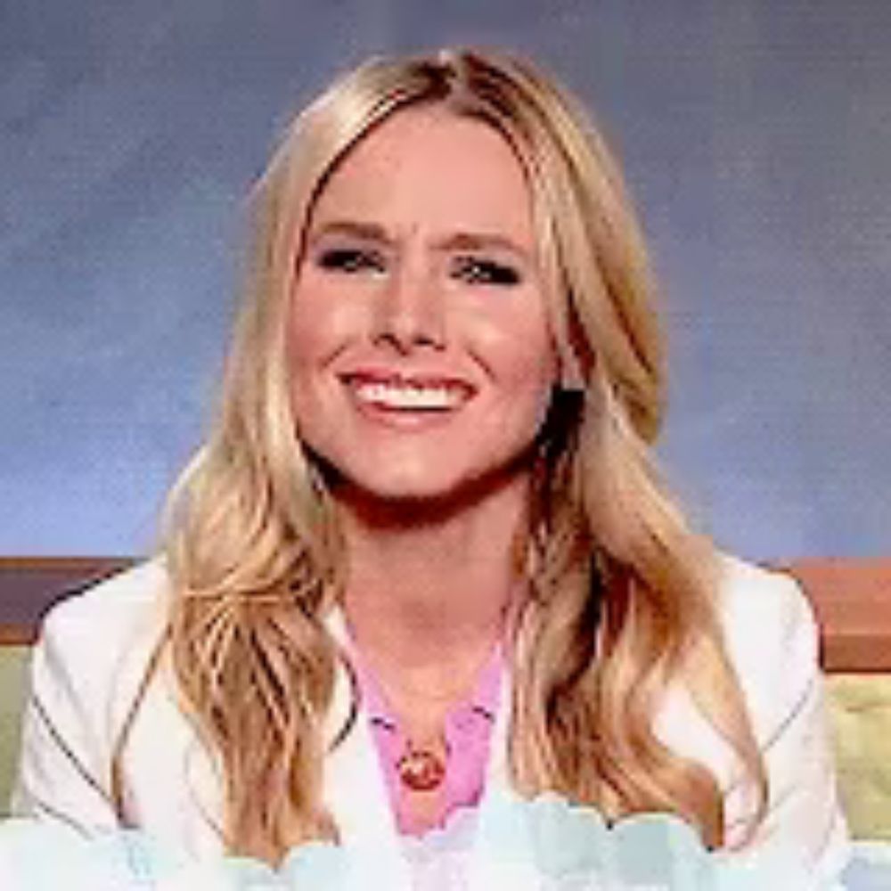 a woman with long blonde hair is smiling and wearing a white jacket and a pink shirt .