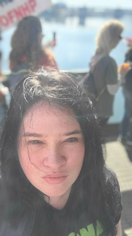 Hazy picture of me (a remarkably youthful looking woman on the eve of her 47th birthday, a little like maybe a cousin of Janean garofalo) on the steel bridge the Willamette River is in the background and visible is a sign for OFNHP union